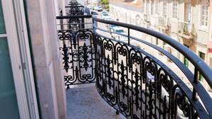 A balcony with ornate black wrought iron railings overlooking a street with parked cars and buildings. - President Pais Apartment (Faro)