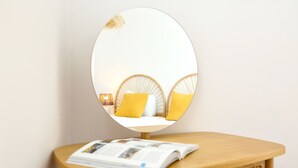 A round mirror on a wooden table with a magazine. - President Pais Apartment (Faro)
