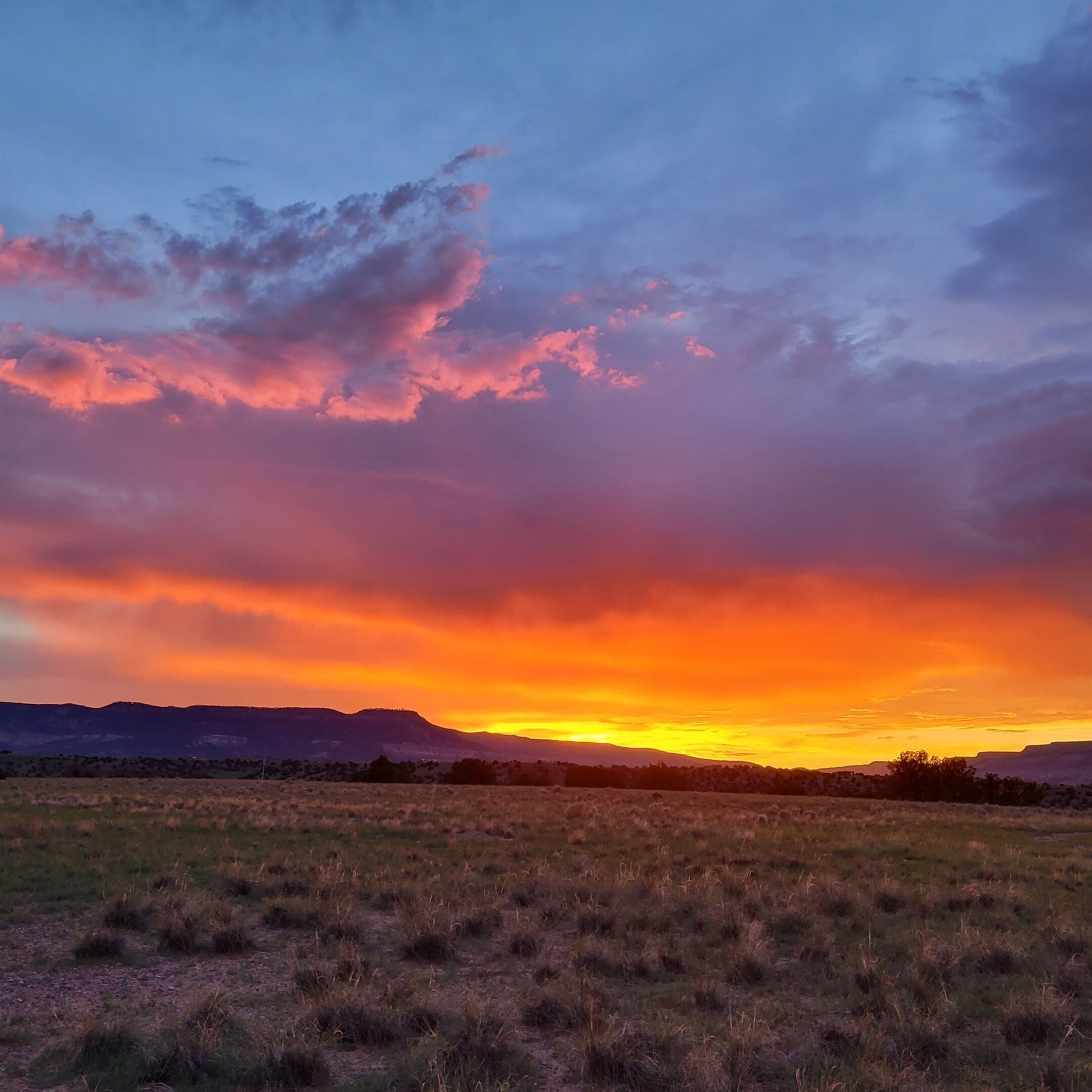 A sunset over a flat landscape with distant mountains.