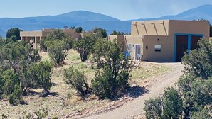 Paisaje rural con edificios de adobe tradicionales, un camino de tierra y vegetación escasa.