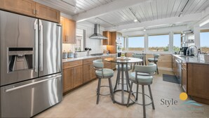 A modern kitchen with stainless steel appliances, wooden cabinets, and a central island with bar stools.