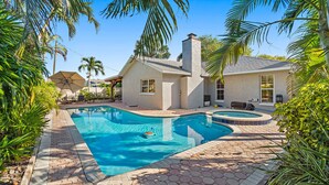 Una casa con piscina, patio y zona de estar cubierta.