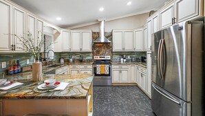 Una cocina moderna con armarios blancos, un refrigerador de acero inoxidable e una isla central con encimera de mármol.