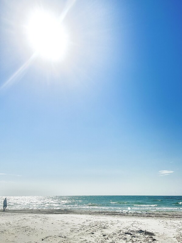 Uma praia com céu limpo e o sol brilhando.
