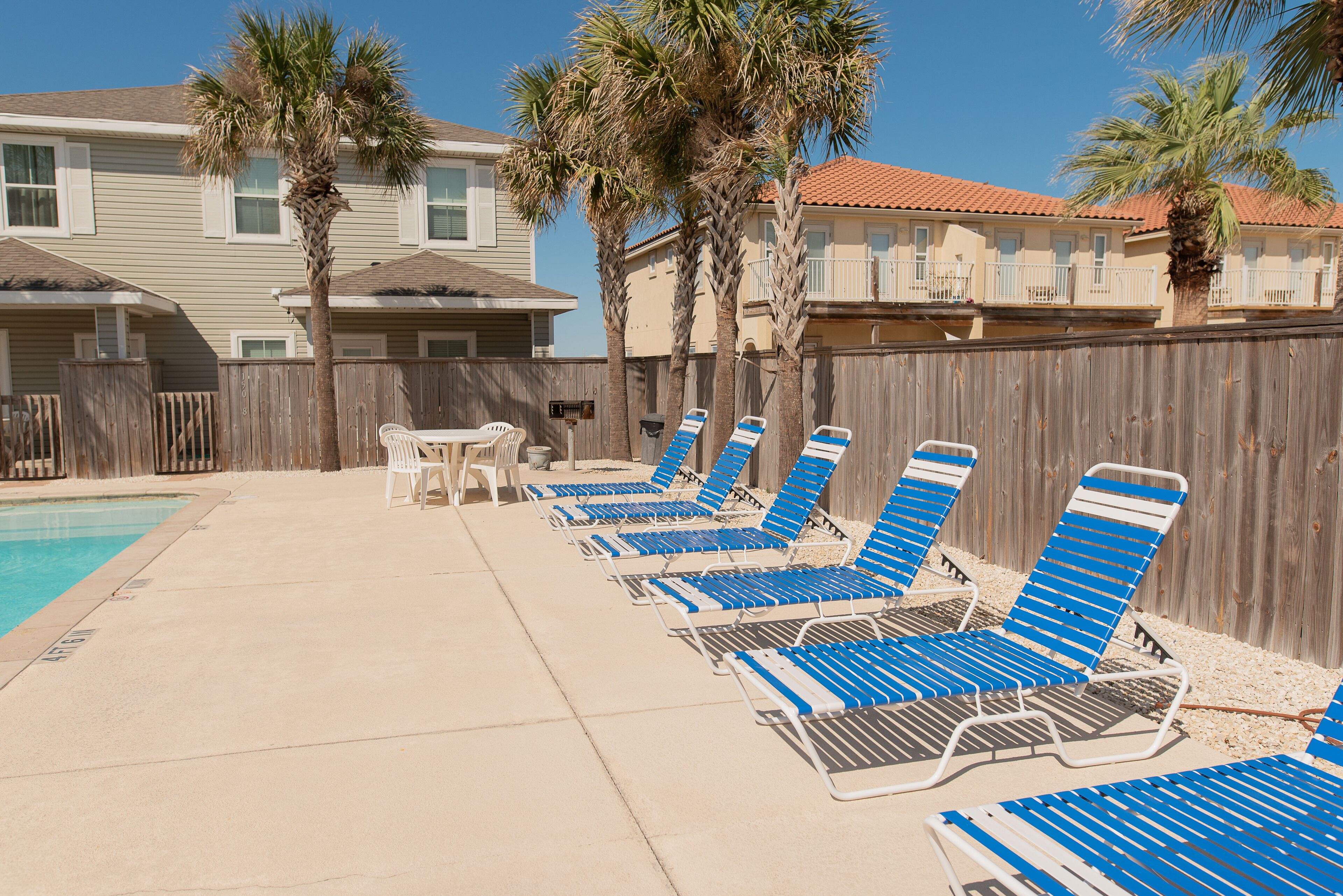 Un espace aménagé au bord de la piscine, avec des chaises longues et une clôture en bois.