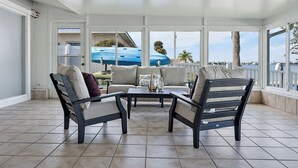 Una sala de estar con ventanales y vista al mar, con un sofá, dos sillones y una mesa de centro.