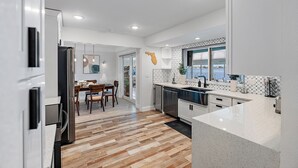Una cocina moderna con suelo de madera, armarios blancos y una isla grande.