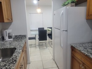 A kitchen with granite countertops, a white refrigerator, and a dining area with a table and chairs. - 1 BR Apt. Awesome Location. Near FLL Beach and Las Olas (Fort Lauderdale)