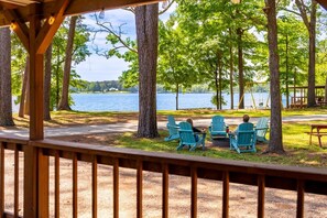 A lakeside view with a gazebo, chairs, and a picnic table.