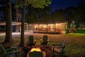 Una cabaña con terraza, fogata y asientos exteriores.