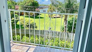 Ein Balkon mit Blick auf eine grüne Rasenfläche und einen Holzzaun.
