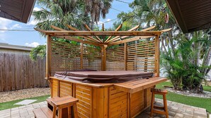 Tinaco de madera con una pérgola de madera encima, rodeado por una valla de madera y palmeras.