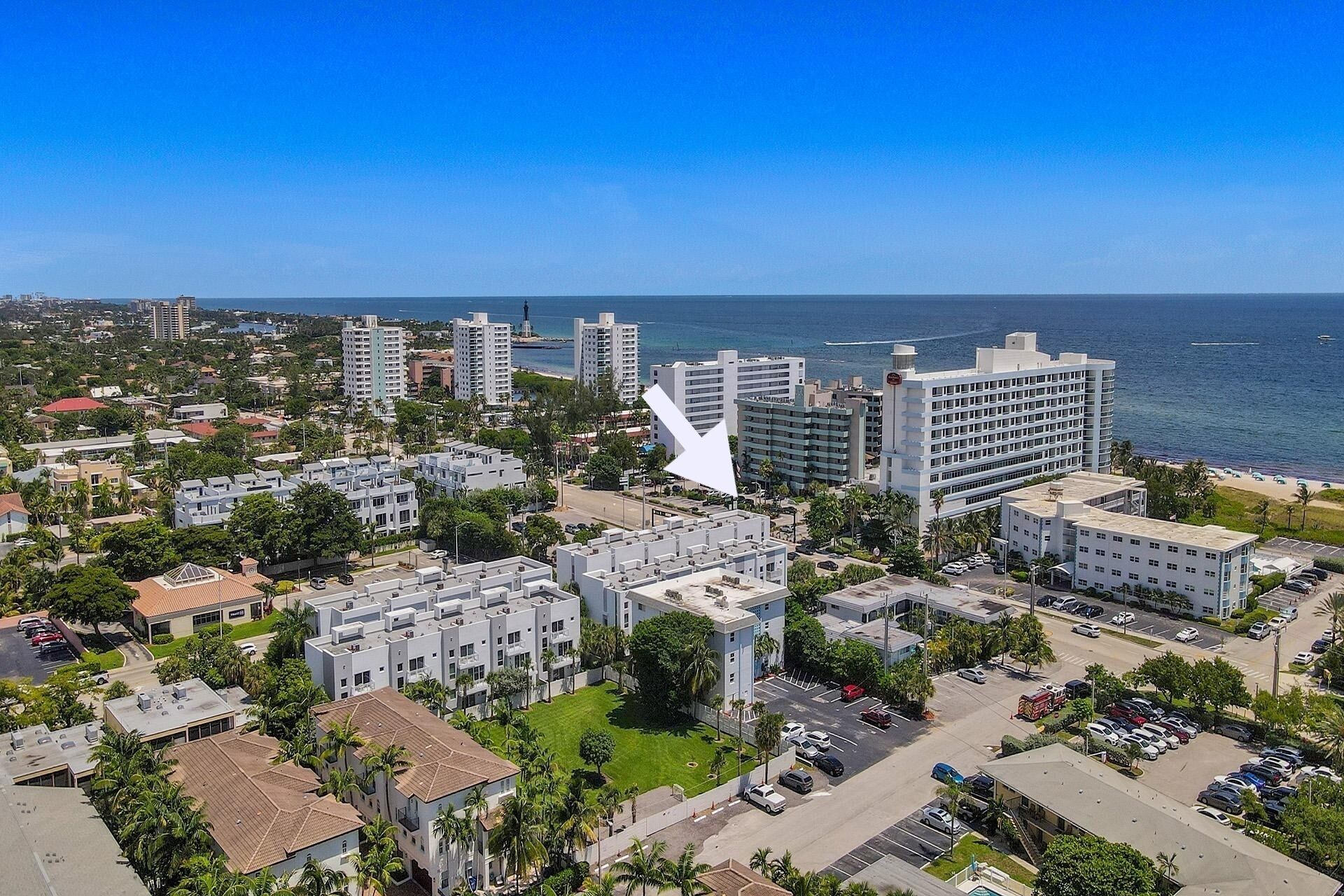 An aerial view of a coastal city with high-rise buildings, a marina, and a clear blue sky.