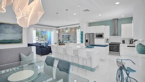 Una cucina moderna con mobili bianchi, elettrodomestici in acciaio inossidabile e un'isola centrale.