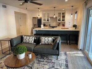 A modern living room with a grey sofa, a coffee table with a plant, and a patterned rug.