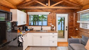 Una cabaña con cocina, comedor y vista al lago.