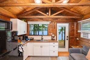 Une cabane avec une cuisine, un coin repas et une vue sur le lac.