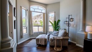 Ein geräumiges Zimmer mit großem Fenster, einer Couch, einem kleinen Tisch und einer Topfpflanze.
