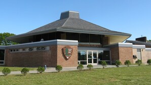 Un bâtiment à la façade en briques, doté d’une grande entrée avec des portes vitrées et d’une enseigne indiquant qu’il s’agit d’un bâtiment du Service des parcs nationaux.
