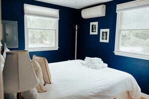 A bedroom with a bed, white linens, a lamp, and a window with a view of trees. - Modern Cape Cod Cottage Close to Everything - outdoor shower! (Eastham)