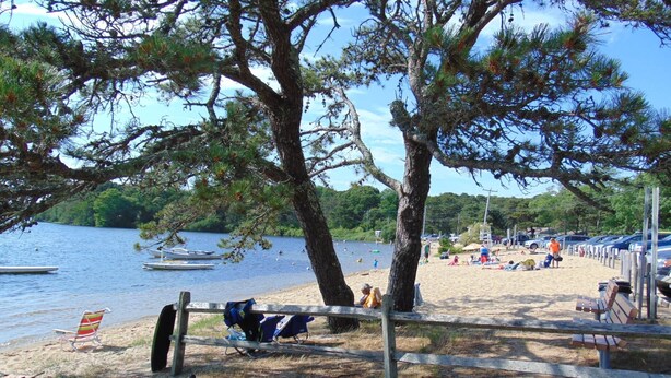 Une plage au bord du lac, avec des bateaux, une zone sablonneuse et une clôture en bois.