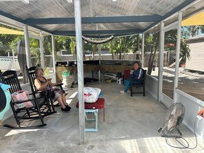 A covered outdoor seating area with a grill, rocking chairs, and a fan. - Cozy & Private Home at US Coral Reef Capital (Key Largo)