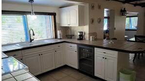 A kitchen with white cabinets, a dishwasher, a coffee maker, and a trash can. - Cozy & Private Home at US Coral Reef Capital (Key Largo)
