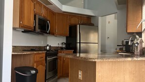 Una cocina con armarios de madera, un refrigerador de acero inoxidable, un microondas, un horno y un ventilador de techo.