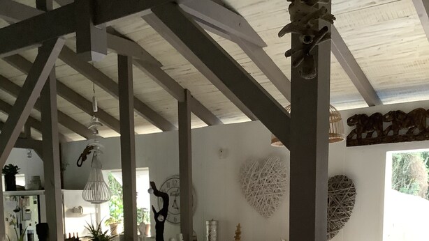 A spacious living area with a wooden sofa, a coffee table with decorative items, and a kitchen area with a clock and various kitchenware. - PROMO: CHARMING POOL VILLA LES TROIS ILETS 3 bedrooms sleeps 8. WATCH  (Les trois ilets)