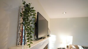 A modern living room with a flat-screen TV mounted on a white mantelpiece above a fireplace. - Guest Fave Cape-Cod Style Retreat with Main-Level Bedroom bordering Farmington (New Britain)