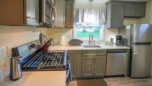 Cocina con estufa a gas, electrodomésticos de acero inoxidable y armarios de madera.