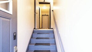 Uma escadaria leva a uma porta com um lustre acima.