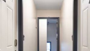 Um corredor estreito com portas brancas em ambos os lados.