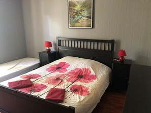 A neatly made bed with a floral bedspread and two red lamps on side tables.