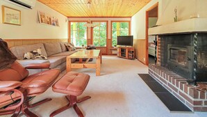 Una sala de estar acogedora con un sofá, sillones de cuero, una mesa de centro, una chimenea y una televisión.