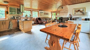 Una cocina amplia con armarios de madera, un comedor con una mesa grande y sillas de madera, y una sala de estar acogedora con sofá y chimenea.