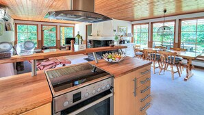 Una cocina moderna con encimeras de madera, horno empotrado y un amplio ventanal con vistas a zonas verdes.
