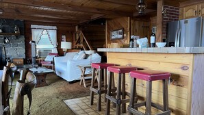 Interior acogedor de una cabaña con barra de madera, sofá y chimenea.