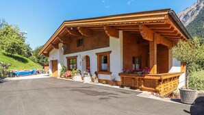 A two-story wooden chalet with a balcony, white walls, and a stone foundation. - gemuetliche Ferienwohnung (Dalaas)
