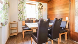 A dining area with a wooden table, black leather chairs, and a hanging light fixture. - gemuetliche Ferienwohnung (Dalaas)