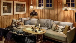 A cozy room with wooden walls, a sofa, a table with a candle, and framed pictures on the wall. - Beautiful home in Uvdal with kitchen (Uvdal)