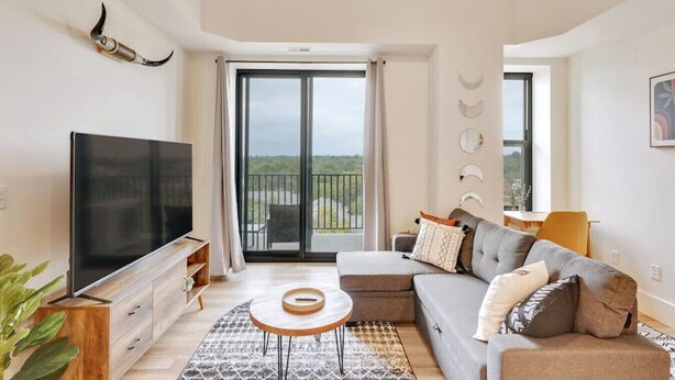 Un salon moderne doté d’un téléviseur à écran plat, d’un canapé, d’une table basse et d’un balcon offrant une vue agréable.