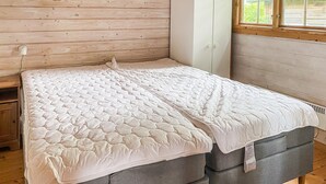 A bed with a quilted white mattress in a room with wooden walls and a window. - Cozy home in Bogø By with WiFi (Bogø By)