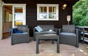 An outdoor seating area with wicker furniture, a table, and a window with curtains. - Cozy home in Bogø By with WiFi (Bogø By)