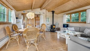 A cozy cabin interior with a dining area, a sofa, and a fireplace. - Cozy home in Bogø By with WiFi (Bogø By)