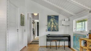Een kamer met een piano, een kaart en een ingelijst schilderij aan de muur.