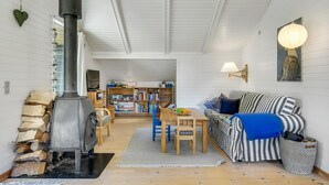Een gezellige woonkamer met een open haard, een gestreepte bank, een boekenkast en een eethoek.