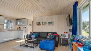 Ett modernt vardagsrum med en soffa, ett soffbord och utsikt över naturen.