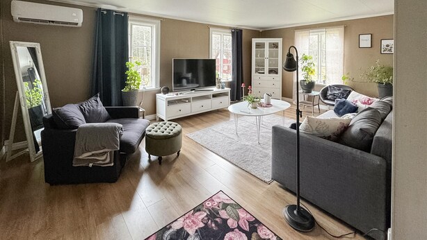 Una sala de estar con dos sofás, una mesa de centro, un televisor y un aparador.