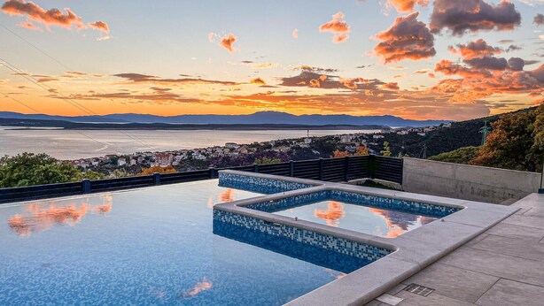 Ein Pool mit unendlicher Kante und Blick auf Stadt und Berge.